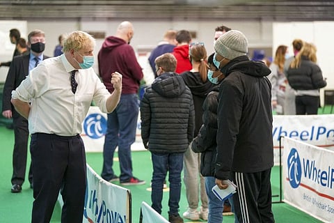 Prime Minister Boris Johnson speaks to a man waiting to receive a dose of a vaccine during his visit to a vaccination hub in the Guttman Centre at Stoke Mandeville Stadium in Aylesbury, north west of London, on January 3, 2022. 