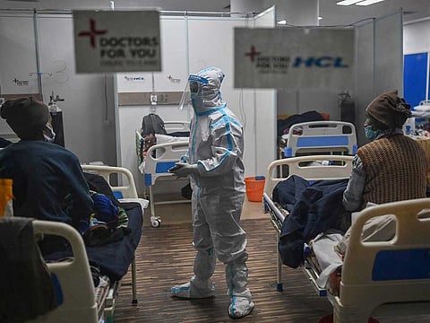 A health worker wearing Personal Protective Equipment (PPE) suit interacts with patients inside a ward at the Commonwealth games (CWG) village sports complex, temporarily converted into Covid-19 coronavirus care centre, in New Delhi on January 5, 2022.