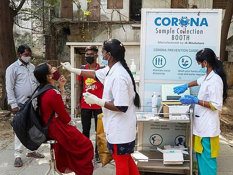 A health worker takes a nasal swab sample of a woman to test for COVID-19 in Hyderabad, India, Wednesday, Jan. 5, 2022.