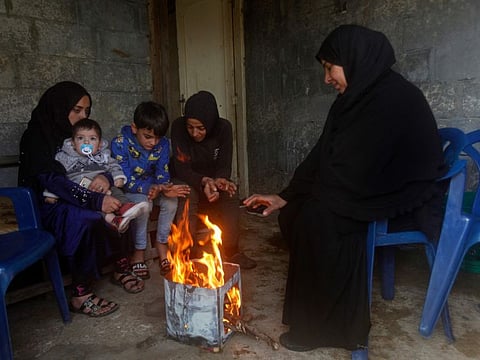 Syrian refugees warm themselves around a bonfire outside their small house, in Sarafand village near the southern port city of Sidon, Lebanon, Sunday, Jan. 2, 2022. An official in a Lebanese rescue group says a mother and her three children died in their sleep after inhaling toxic fumes from burning coal to warm their room in a village in southern Lebanon. Lebanon, a country of 6 million people, is home to 1.5 million Syrians who fled the now decade-old civil war in their country. (AP Photo/Mohammed Zaatari)