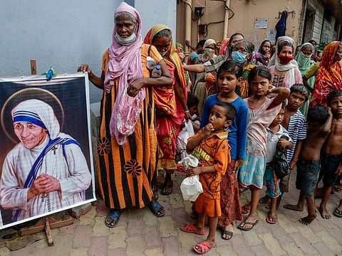 Homeless people gather beside a portrait of Saint Teresa, the founder of the Missionaries of Charity, to collect food in Kolkata, in a file picture.