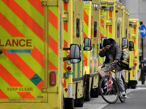 A man cycles between ambulances parked outside of the Royal London Hospital, amid the spread of the coronavirus disease (COVID-19) pandemic in London, Britain, January 7, 2022.