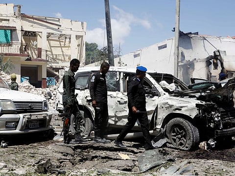Somali security officers look at the wrecked vehicles at the scene of an explosion in the Hamarweyne district of Mogadishu, Somalia, January 12, 2022. 