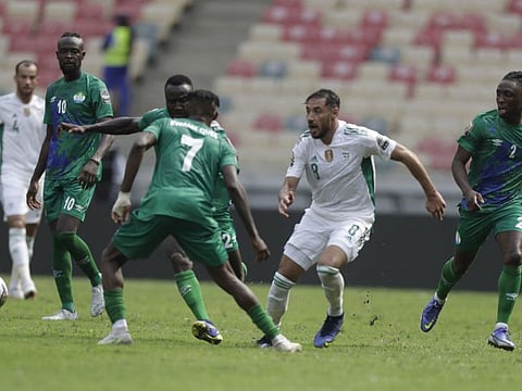 Algeria’s Mohamed Belaili, centre, is challenged by Sierra Leone's Kwame Quee, left, during the African Cup of Nations 2022 group E soccer match between Algeria and Sierra Leone at the Japoma Stadium in Doula, Cameroon.