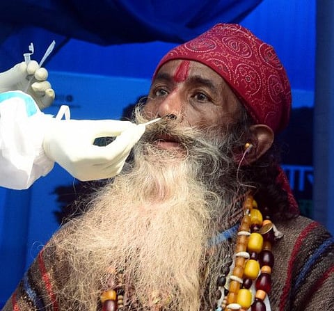 A healthcare worker collects the nasal swab sample of a sadhu for COVID testing at Babughat transit camp during his journey to attend Ganga Sagar Mela.