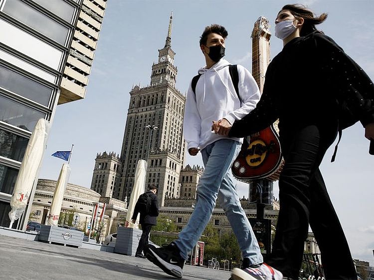 People wearing protective masks walk in  in Warsaw, Poland. 