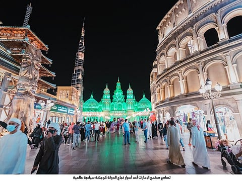 Visitors at Global Village, with the many illuminated pavilions of different countries forming a perfect backdrop.