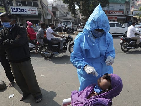 A health worker takes a swab sample of a woman for COVID-19 testing in Ahmedabad, on January 17, 2022. 