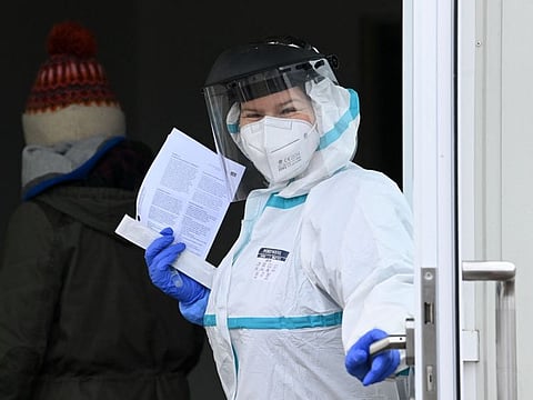 A medic lets a woman enter in a swab room of a test centre in Unterschleissheim near Munich, southern Germany, on January 18, 2022.