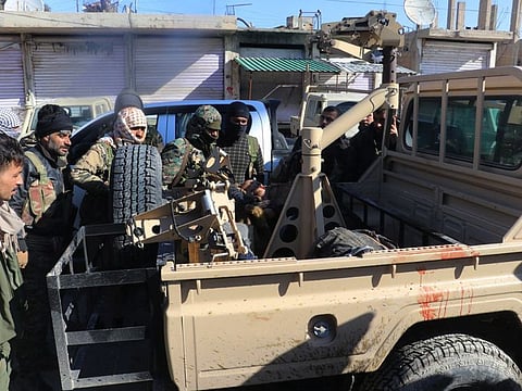 Fighters from the Kurdish-led Syrian Democratic Forces gather around a body of Daesh terror group gunman who was killed after they attacked Gweiran Prison, in Hassakeh, northeast Syria on January 21, 2022. 