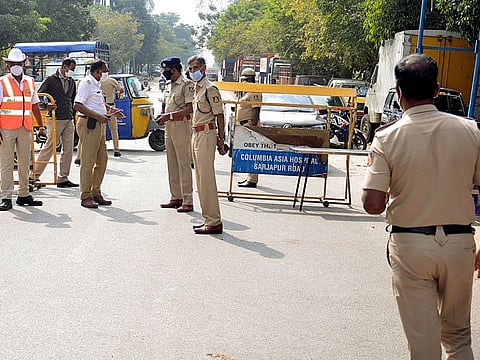 Karnataka Police stand guard at a checkpoint during a weekend curfew imposed by the state government to curb the spread of COVID-19 and Omicron cases, in Bengaluru on Saturday, Jan 8, 2021.