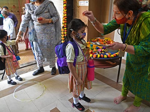A teacher welcomes a student upon her arrival at a school in Mumbai on January 24, 2022, after schools that were closed as a preventive measure to curb the spread of the Covid-19 coronavirus were reopened.
