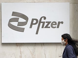 A person walks past a Pfizer logo in the Manhattan borough of New York City. 