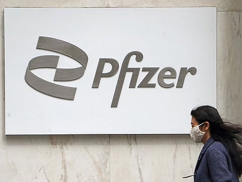 A person walks past a Pfizer logo in the Manhattan borough of New York City. The arrival of a pill that can be taken at home at the first sign of symptoms is sparking optimism about the course of the pandemic