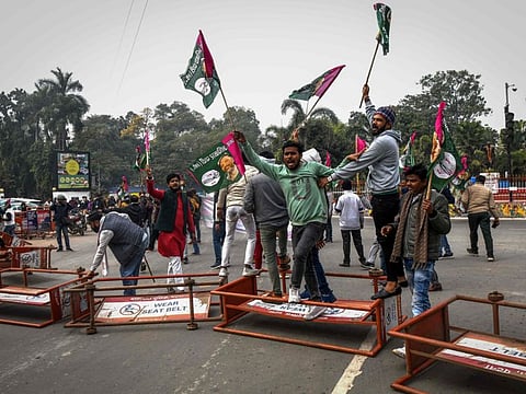 Activists from All India Students Association (AISA) and other affiliations shout slogans while standing on overturned police barricades during a state-wide strike to protest against access to railway jobs in Patna on January 28, 2022.