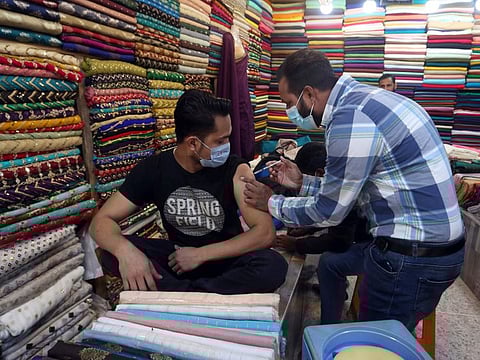 A shopkeeper, left, receives the Pakvac COVID-19 vaccine from a health worker at a market in Karachi.