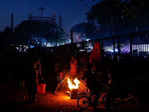 Family of homeless people gather around a bonfire to beat the cold, in New Delhi on January 27, 2022. 