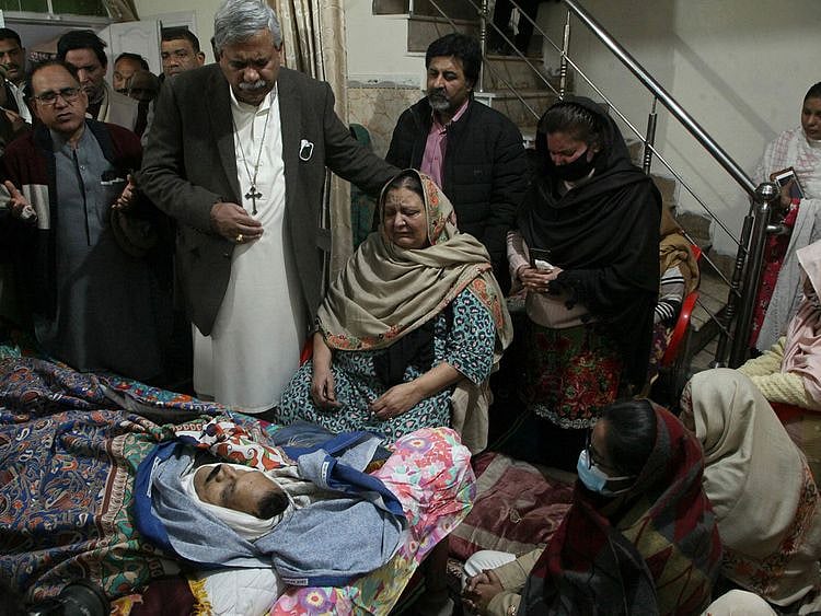 Relatives of Christian priest Father William Siraj, 75, who was killed by unknown gunmen, mourn next to his body at his home in Peshawar on January 30, 2022.