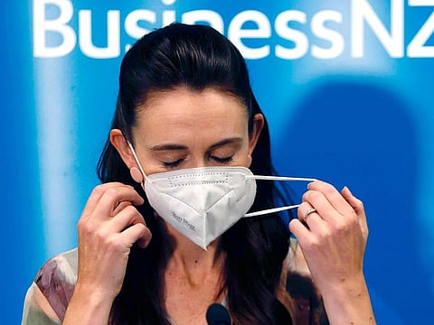 New Zealand Prime Minister Jacinda Ardern removes her mask before she outlines the Government's plans, Thursday, Feb. 3, 2022, that will dismantle its quarantine system and reopen its borders the world. 