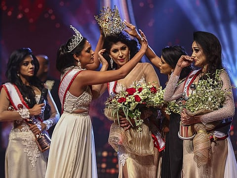 In this file photo taken on April 4, 2021 winner of Mrs Sri Lanka 2020 Caroline Jurie (2-L) removes the crown of 2021 winner Pushpika de Silva (C) as she is disqualified over the accusation of being divorced, at a beauty pageant for married women in Colombo.