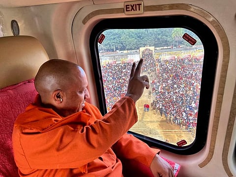 Uttar Pradesh Chief Minister Yogi Adityanath shows victory sign to the crowd from a helicopter as he leaves after an election rally in Muradabad, on February 8, 2022. The polls are a referendum on the saffron-robed Adityanath, a poster figure for the Hindu right-wing, who some analysts believe is vying to be the next prime minister.  