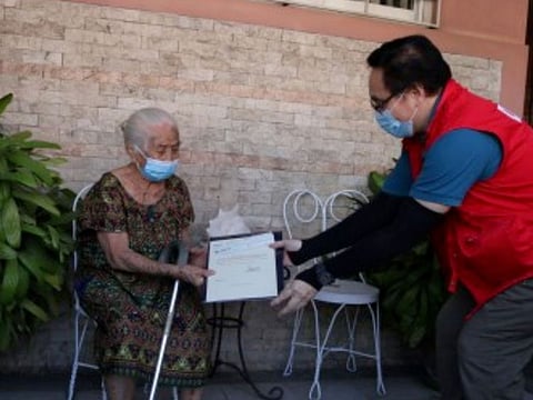 A centenarian receives a plaque signed by the president and a cash gift of Php100,000 (about $2,000) from a Department of Social Welfare and Development (DSWD) official. 