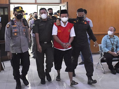 Security officers escort Herry Wirawan, the principal of a girls-only Islamic boarding school who is accused of raping his students, during a sentencing hearing at a district court in Bandung, West java, Indonesia, on February 15, 2022.  