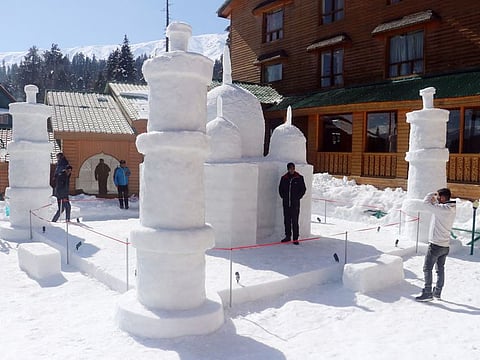A tourist poses for a picture in front of a replica of the Taj Mahal made up of ice, at Grand Mumtaz Resorts, in Gulmarg.