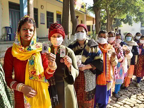 People stand in a queue to cast their votes for the Punjab State Assembly elections in village Chogawan, outskirts of Amritsar on February 20, 2022. 