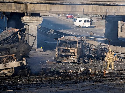 A Ukrainian soldier walks past debris of a burning military truck, on a street in Kyiv, Ukraine, on Saturday, February 26, 2022. 