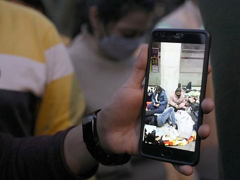 A man shows his mobile phone on which he is on a video call with Indian students stuck in Ukraine, as family and friends of the students demand the Indian Government to evacuate the stranded students, near the Russian embassy in New Delhi, on February 25, 2022. 