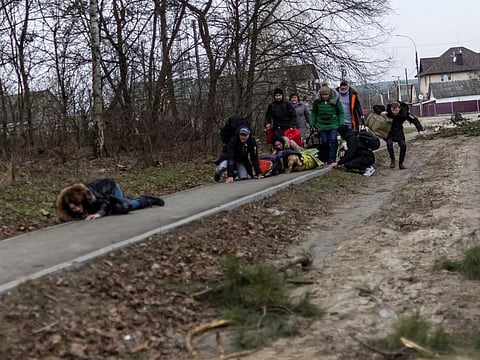 Local residents run for cover as they escape from the town of Irpin, after heavy shelling on the only escape route used by locals, while Russian troops advance towards the capital, in Irpin, near Kyiv, on March 6, 2022. 