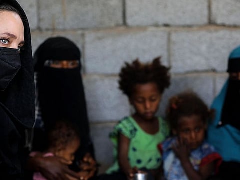 A handout picture made available by the United Nations High Commission for Refugees (UNHCR) on March 6, 2022 shows UNHCR special envoy Angelina Jolie with women and children at a camp for the internally displaced in Yemen's Lahj governorate.