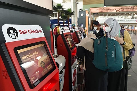 Passengers use a self check-in kiosk ahead of their flight at the Kuala Lumpur International Airport's low-cost carrier terminal in Sepang on March 8, 2022, after authorities announced Malaysia will fully reopen its borders to international travellers from April 1 in an attempt to live with COVID-19. 