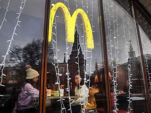 People look out of the window of a McDonald's restaurant as the towers of the Kremlin are reflected in Moscow.