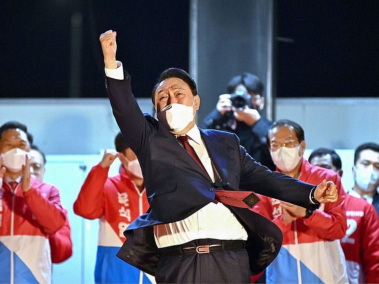 South Korea's new president-elect Yoon Suk Yeol of the main opposition People Power Party gestures to his supporters as he is congratulated outside the party headquarters in Seoul on March 10, 2022.