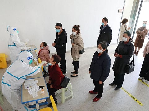 Residents queue to undergo nucleic acid tests for the COVID-19 coronavirus in Hangzhou in China's eastern Zhejiang province on March 11, 2022.
