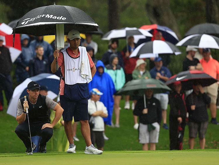 Rory McIlroy lines up a putt in pouring rain at the Players Championship 