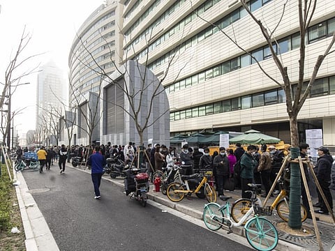 People stand in line at a testing facility outside Dongfang Hospital in Pudong's Lujiazui Financial District in Shanghai, on March 12, 2022.  