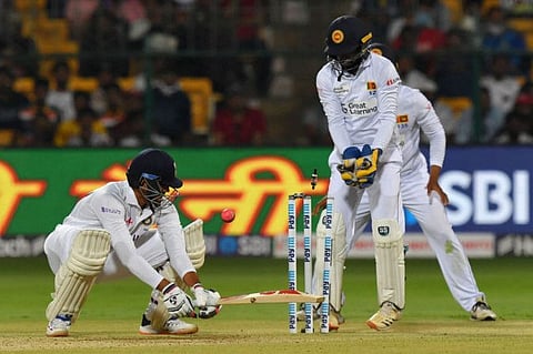 India's Axar Patel (left) is clean bowled by Sri Lanka's Lasith Embuldeniya (not pictured) as Sri Lanka's wicketkeeper Niroshan Dickwella watches during the second day of the second Test cricket match between India and Sri Lanka at the M. Chinnaswamy Stadium in Bangalore.