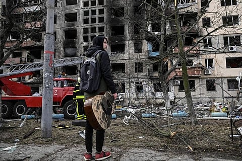 Maksim Korobych, 18-years-old, holds his guitar as he stands in front of a destroyed apartment building after it was shelled in the northwestern Obolon district of Kyiv on March 14, 2022.