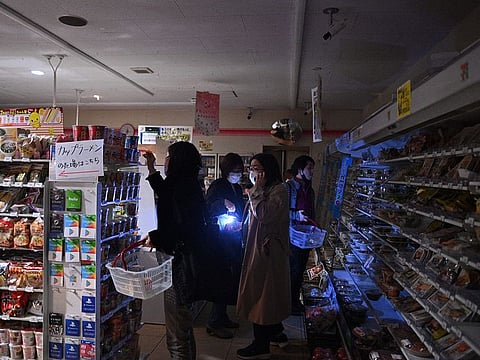 People shop in a store in a residential area during a power outage in Koto district in Tokyo on March 16, 2022, after a powerful 7.3-magnitude quake jolted east Japan. Tokyo Electric Power Company said that around 2 million households were without power.