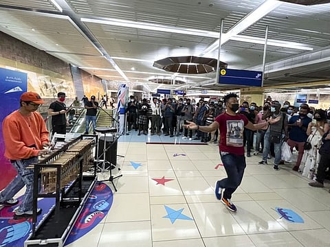 Manshur Praditya (L) playing his angklung that he bought all the way from his hometown in Indonesia, as a metro rider dances while onlookers enjoy the show