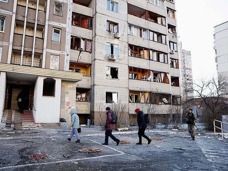 Residents return to a damaged residential building that was hit by an intercepted missile, in Kyiv, on March 17, 2022. 