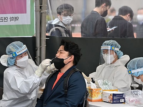 A medical worker takes a nasal swab sample from a man at testing centre in Seoul on March 17, 2022, after South Korea's daily infections rose sharply to hit a new high of over 600,000. 