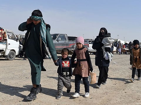 An Afghan migrant family walks in a parking lot before leaving the country for Iran, in Zaranj, in the southwestern province of Nimroz.  