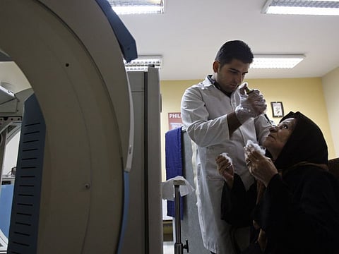 Iranian expert Kouhyar Gervand drops technetium-99 into eyes of Zahra Kohanmanesh for her eye scan at the Shariati hospital, in Tehran, in a file photo.  Iran has converted a fraction of its stockpile of highly enriched uranium into material that can detect cancers and other diseases.  