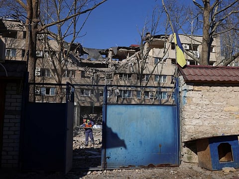 A man cleans the debris in front of a damaged building after a military strike, as Russia's war in Ukraine continues, in Mykolaiv, Ukraine, March 21, 2022.