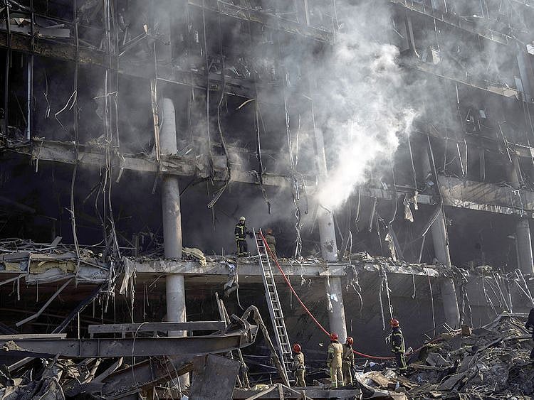 Firefighters try to extinguish a fire amid the destruction caused after shelling of a shopping center, in Kyiv. 