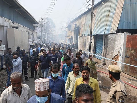 People gather as fire men try to douse a fire that broke out at a scrap warehouse in Secunderabad, on March 23, 2022.  